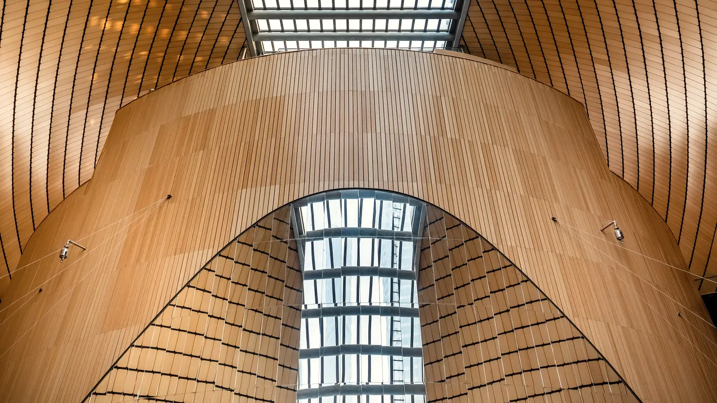 Modern wood-clad concert hall interior with a long glass skylight