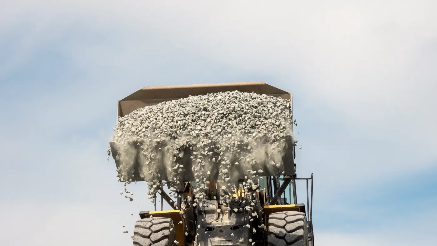 Wheel loader tipping a bucket of gravel against the sky