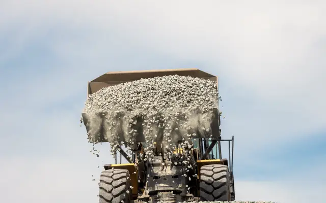 Wheel loader tipping a bucket of gravel against the sky