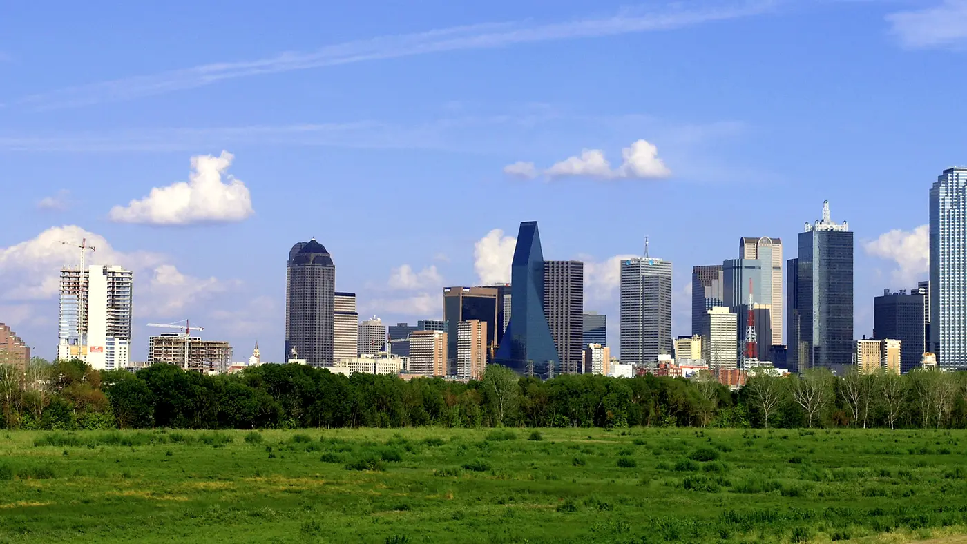 Dallas skyline rising above a green open field