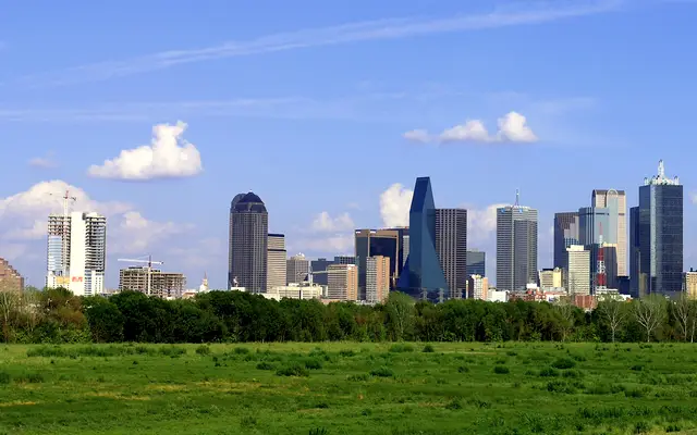 Dallas skyline rising above a green open field