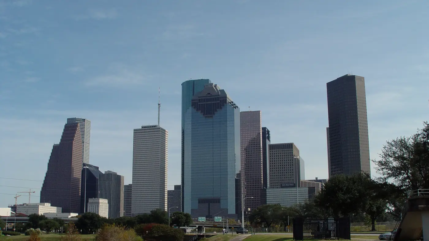 Houston skyline rising above a green park lawn and trees