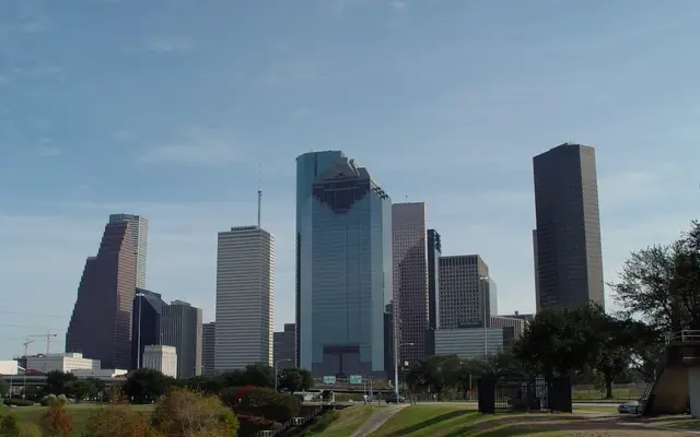 Houston skyline rising above a green park lawn and trees