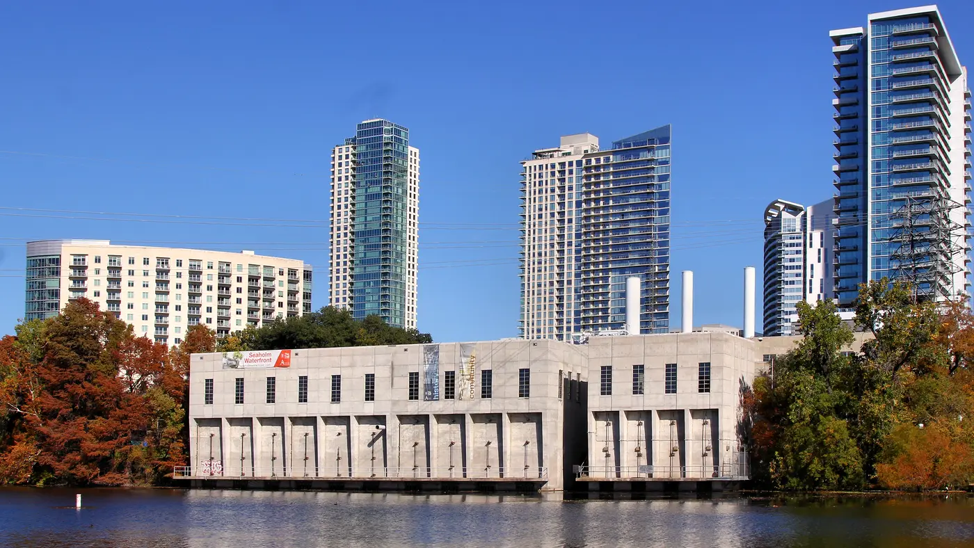 Historic Seaholm intake building with Austin towers and autumn trees