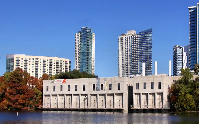 Historic Seaholm intake building with Austin towers and autumn trees
