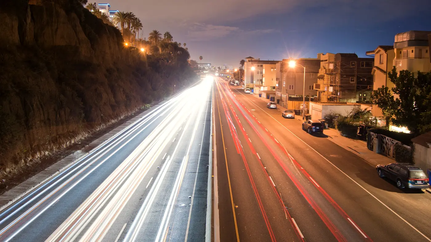 Evening traffic light trails on a highway beside a cliff