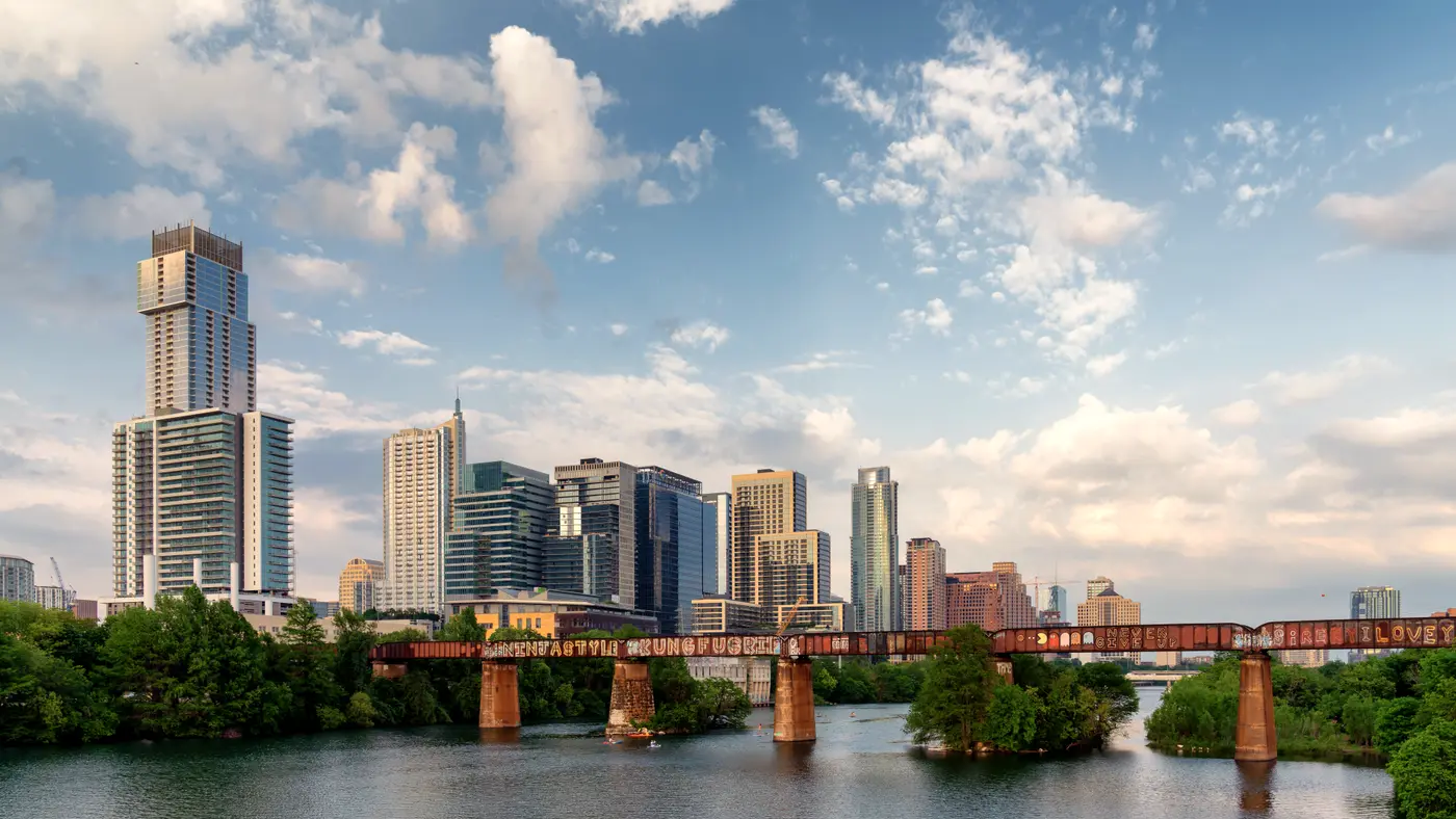 Austin skyline beyond a rusty railroad bridge over Lady Bird Lake