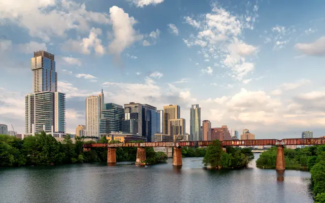 Austin skyline beyond a rusty railroad bridge over Lady Bird Lake