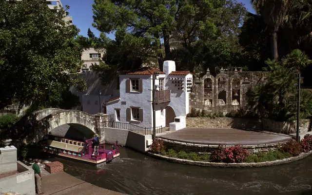 River Walk barge passing the stone bridge and open-air riverside theatre