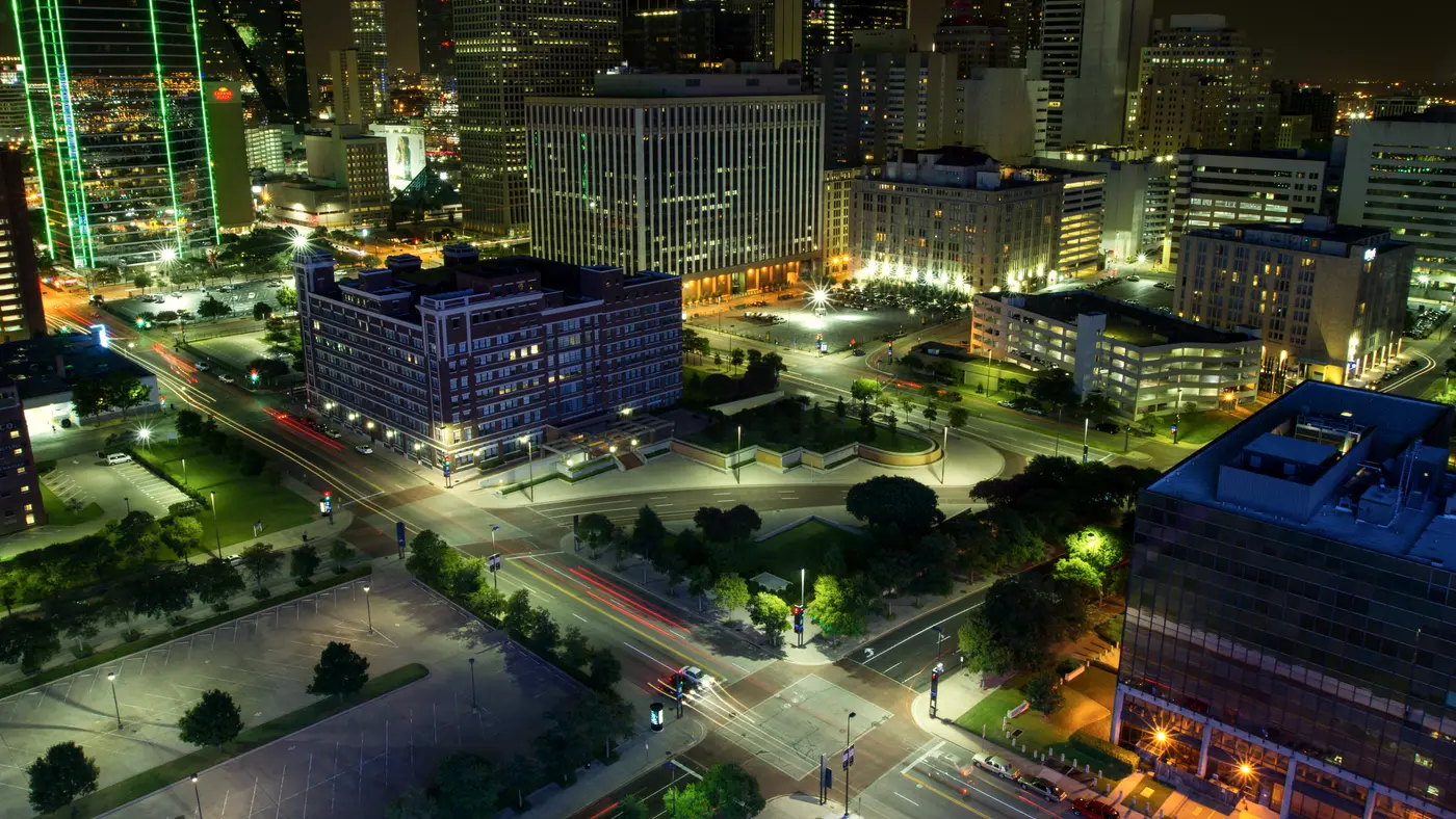 Downtown Dallas at night with lit towers and green-edged skyscraper