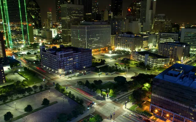 Downtown Dallas at night with lit towers and green-edged skyscraper