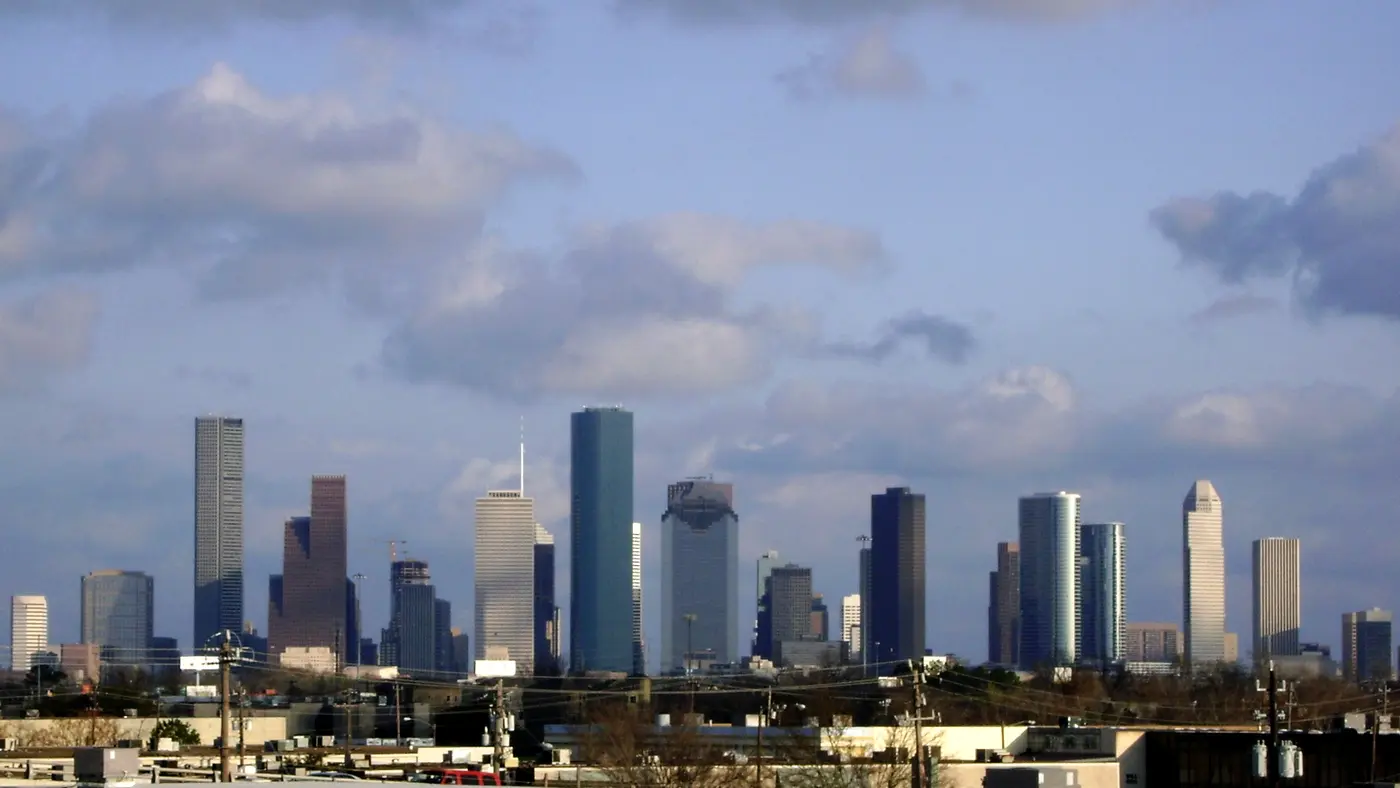 Distant Houston skyline beneath a large sky with scattered clouds