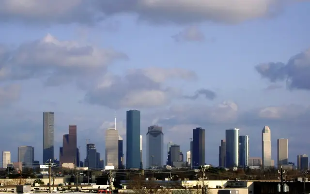 Distant Houston skyline beneath a large sky with scattered clouds