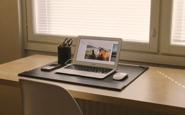 Open laptop on a desk beside a bright window