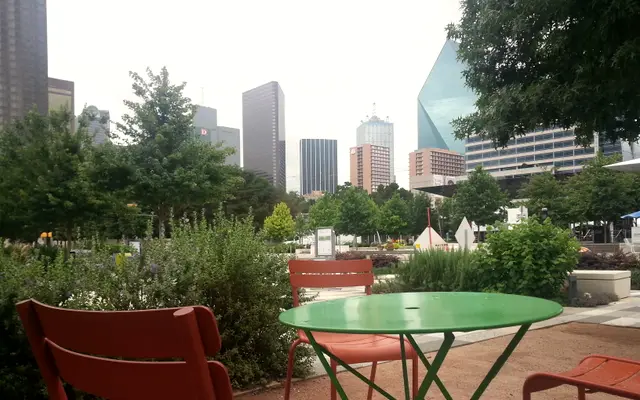 Green cafe table in a Dallas park below skyline towers