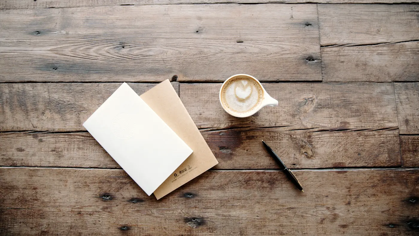 Blank paper, envelope, pen and coffee on a rustic wooden table