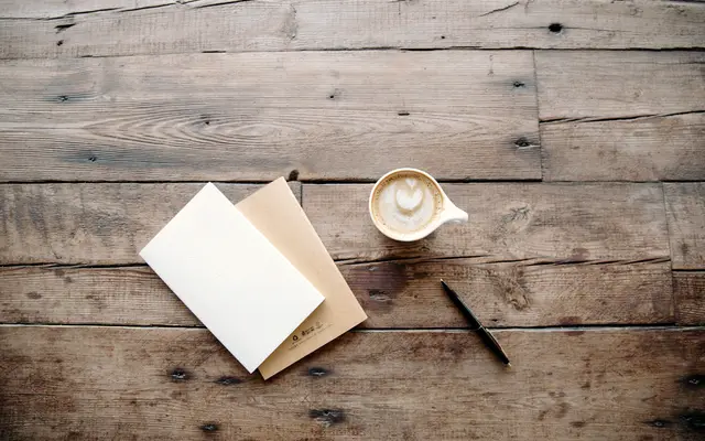 Blank paper, envelope, pen and coffee on a rustic wooden table