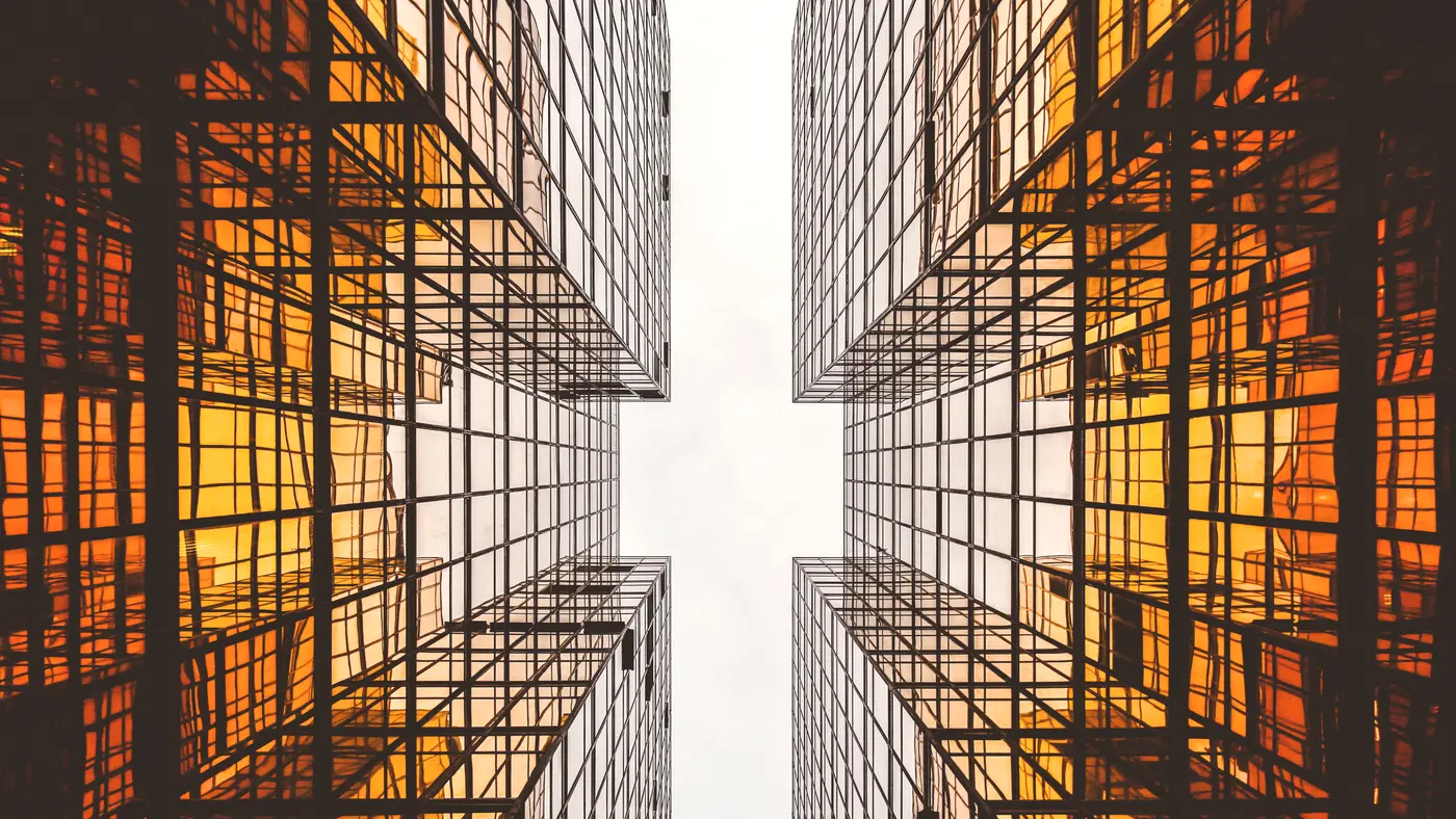 Two glass towers with warm lit windows seen from below