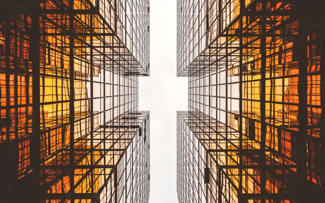 Two glass towers with warm lit windows seen from below