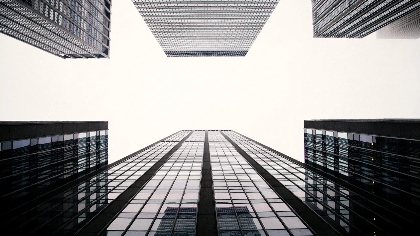 Looking up between modern glass office towers against the sky