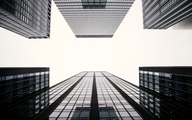 Looking up between modern glass office towers against the sky