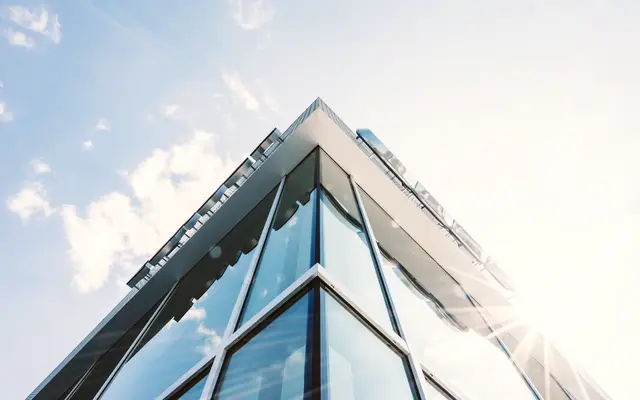 Angular glass building corner against a bright sky