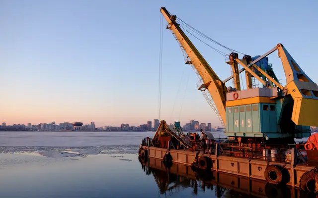Floating crane barge on calm water at dusk