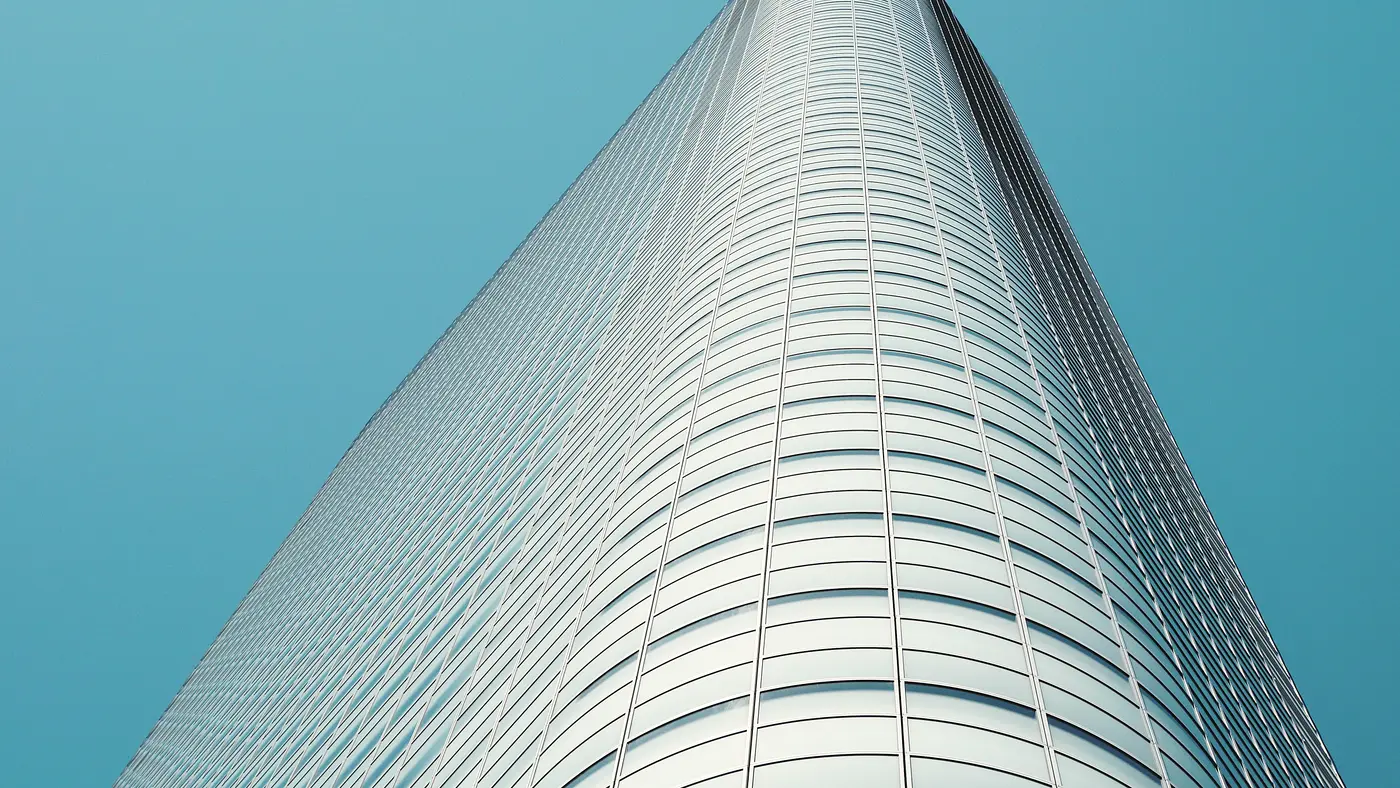 Curved glass skyscraper rising against a clear blue sky