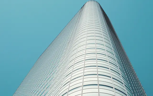 Curved glass skyscraper rising against a clear blue sky