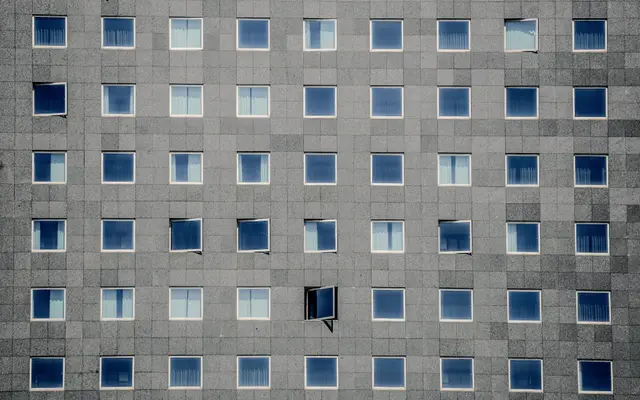 Grid of windows on a grey stone office building facade