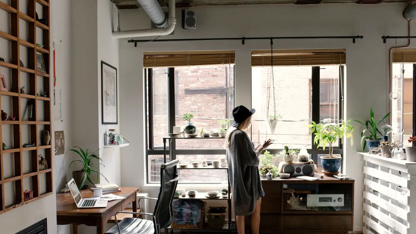 Bright loft office with desk, shelves and a woman by the window