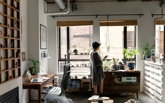 Bright loft office with desk, shelves and a woman by the window