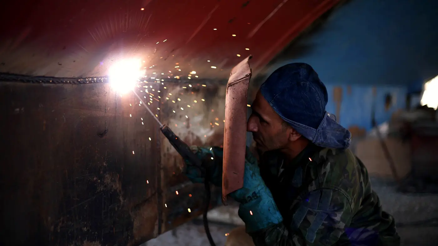 Welder in a mask working on steel with bright sparks