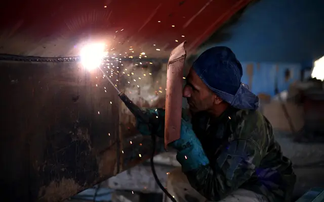 Welder in a mask working on steel with bright sparks