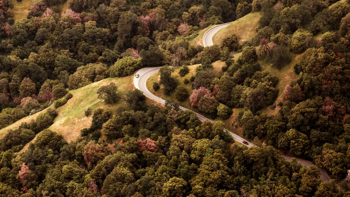 Winding road through wooded hills seen from above