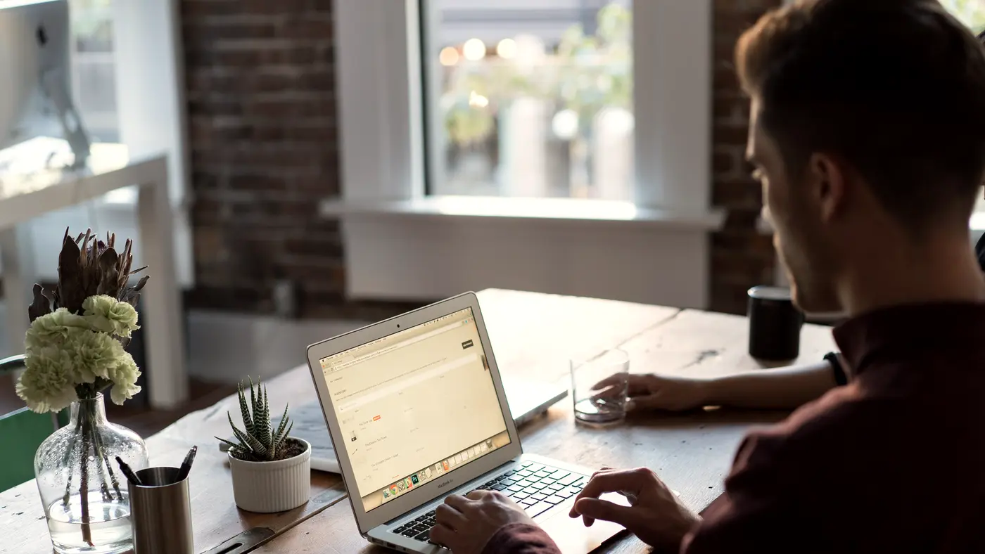 Man working on a laptop at a desk by a window