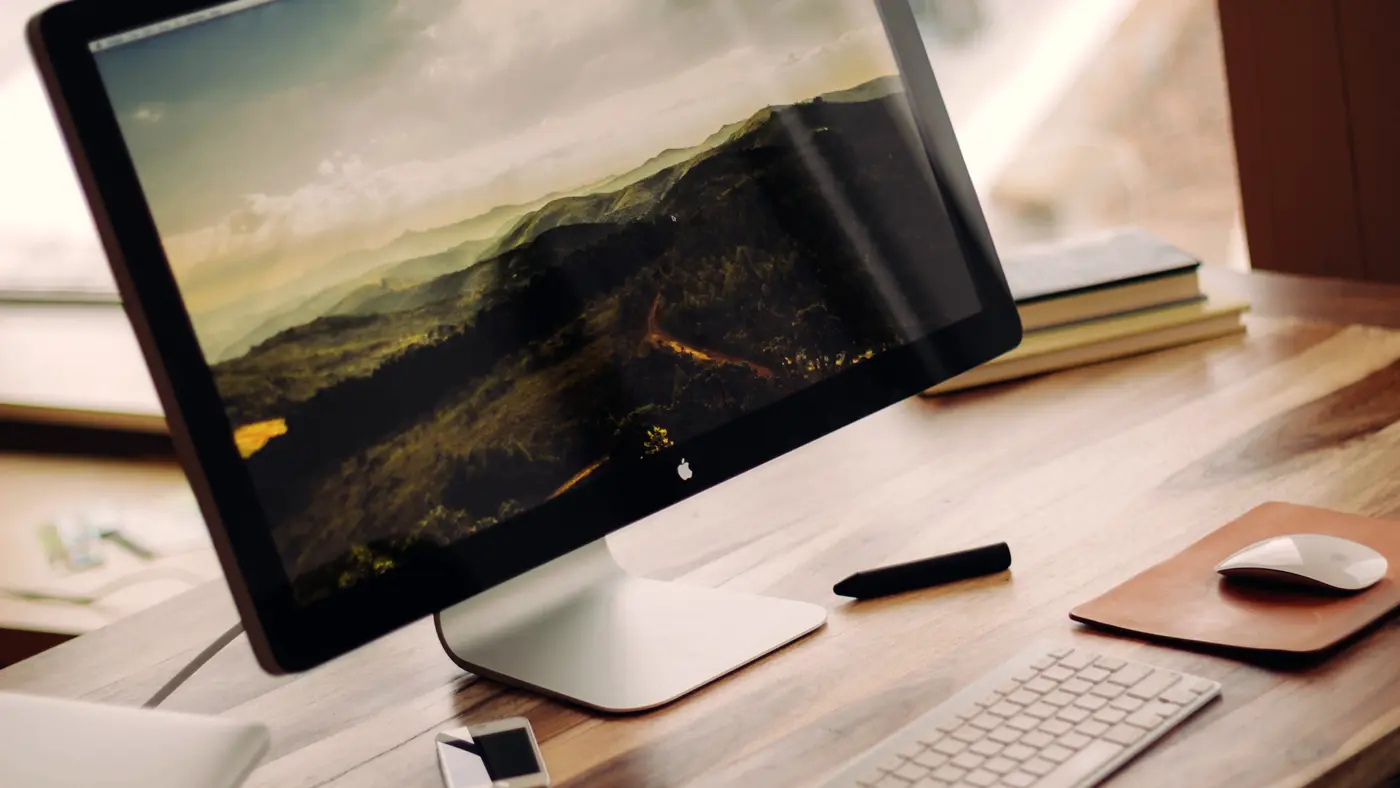 Desktop monitor, keyboard and mouse on a warm wooden desk