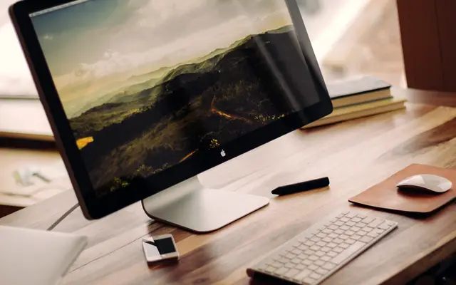 Desktop monitor, keyboard and mouse on a warm wooden desk