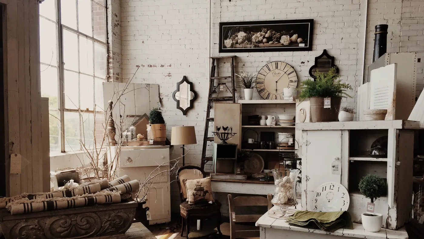 Sunlit antique shop filled with vintage furniture and wall clocks