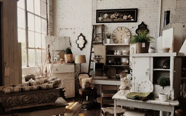 Sunlit antique shop filled with vintage furniture and wall clocks