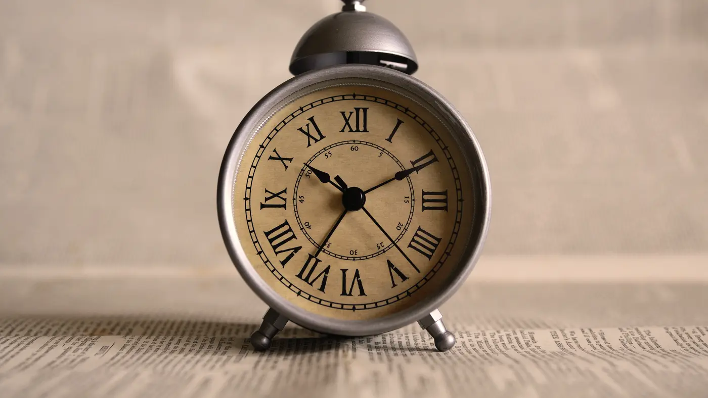 Vintage alarm clock with Roman numerals on a newspaper