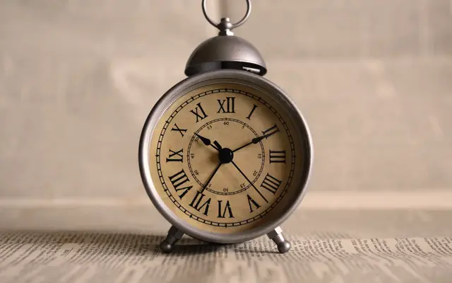 Vintage alarm clock with Roman numerals on a newspaper