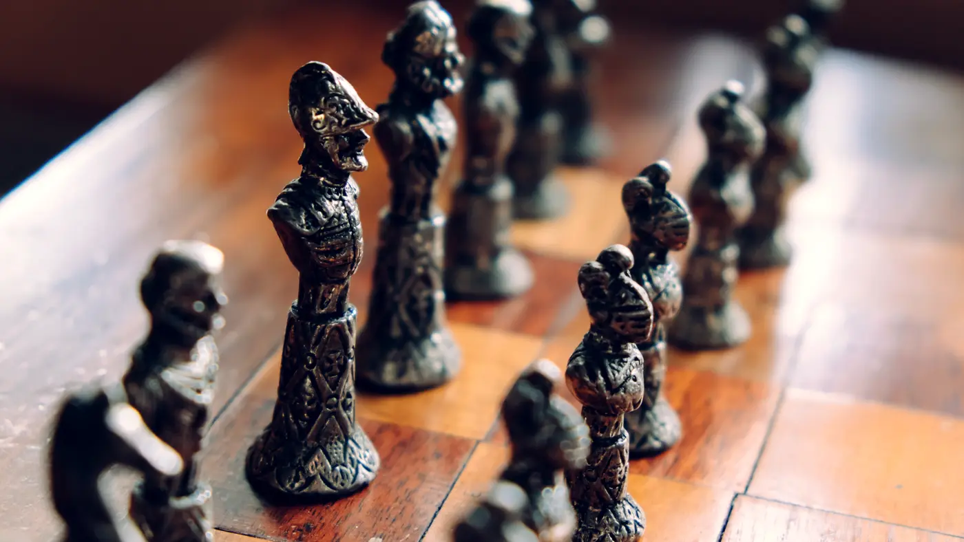 Ornate metal chess pieces lined up on a wooden board