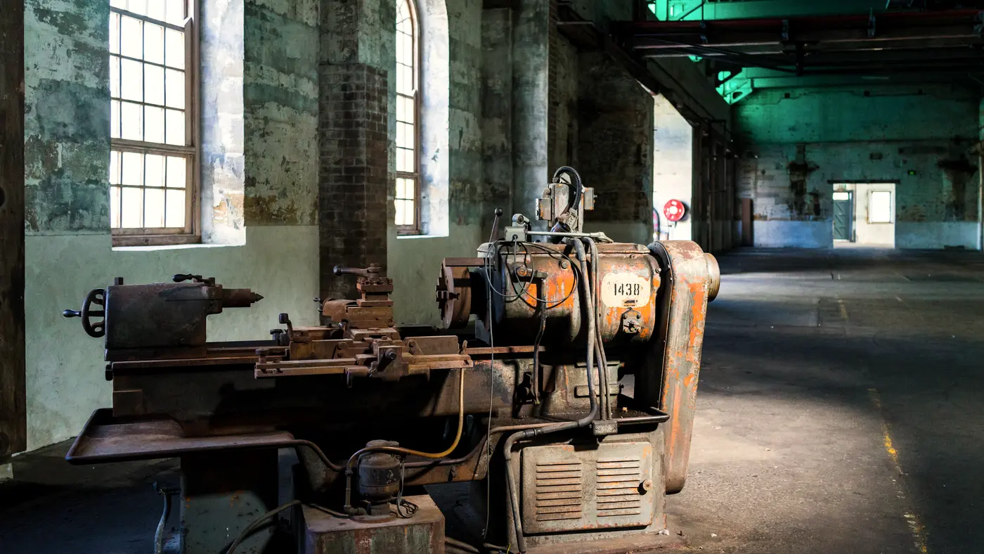 Old metal lathe standing in a large brick factory hall