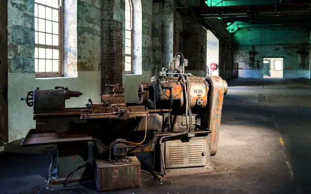 Old metal lathe standing in a large brick factory hall
