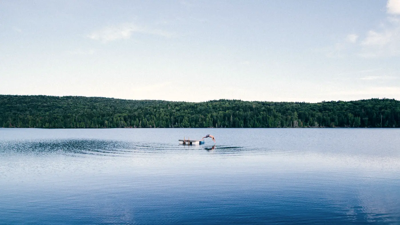 Still blue lake with a small dock and wooded shoreline