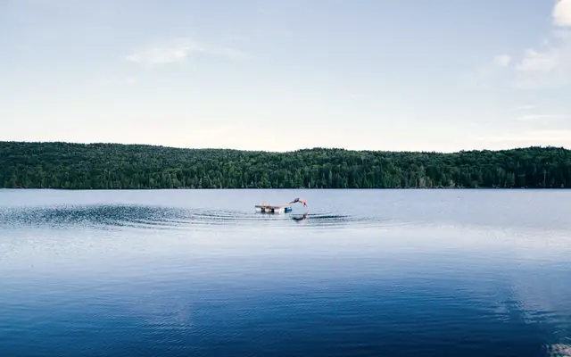 Still blue lake with a small dock and wooded shoreline