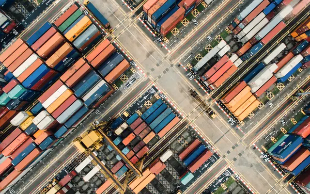 Aerial view of stacked shipping containers and cranes at a port
