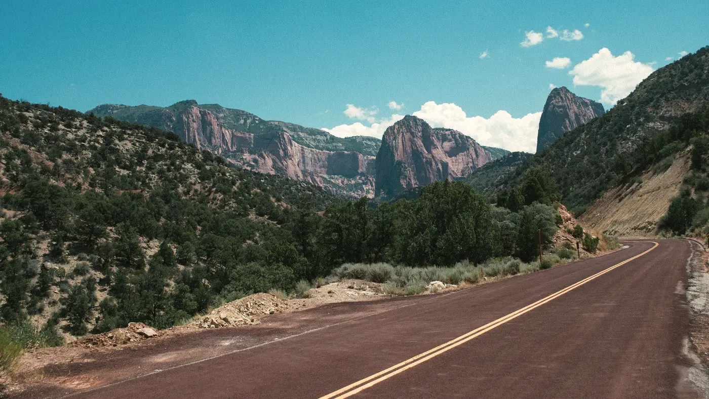 Empty two-lane highway winding through a green canyon valley