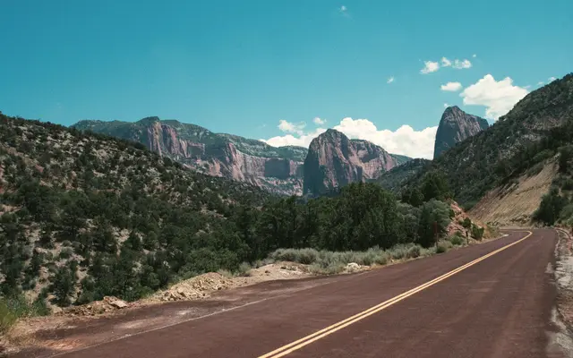 Empty two-lane highway winding through a green canyon valley